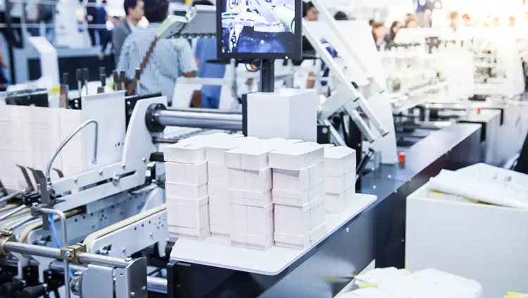 A factory interior showing workers operating machinery, focused on their tasks in a busy industrial environment.