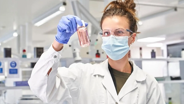 A woman in a lab coat holds a test tube, showcasing her work in a scientific laboratory setting.
