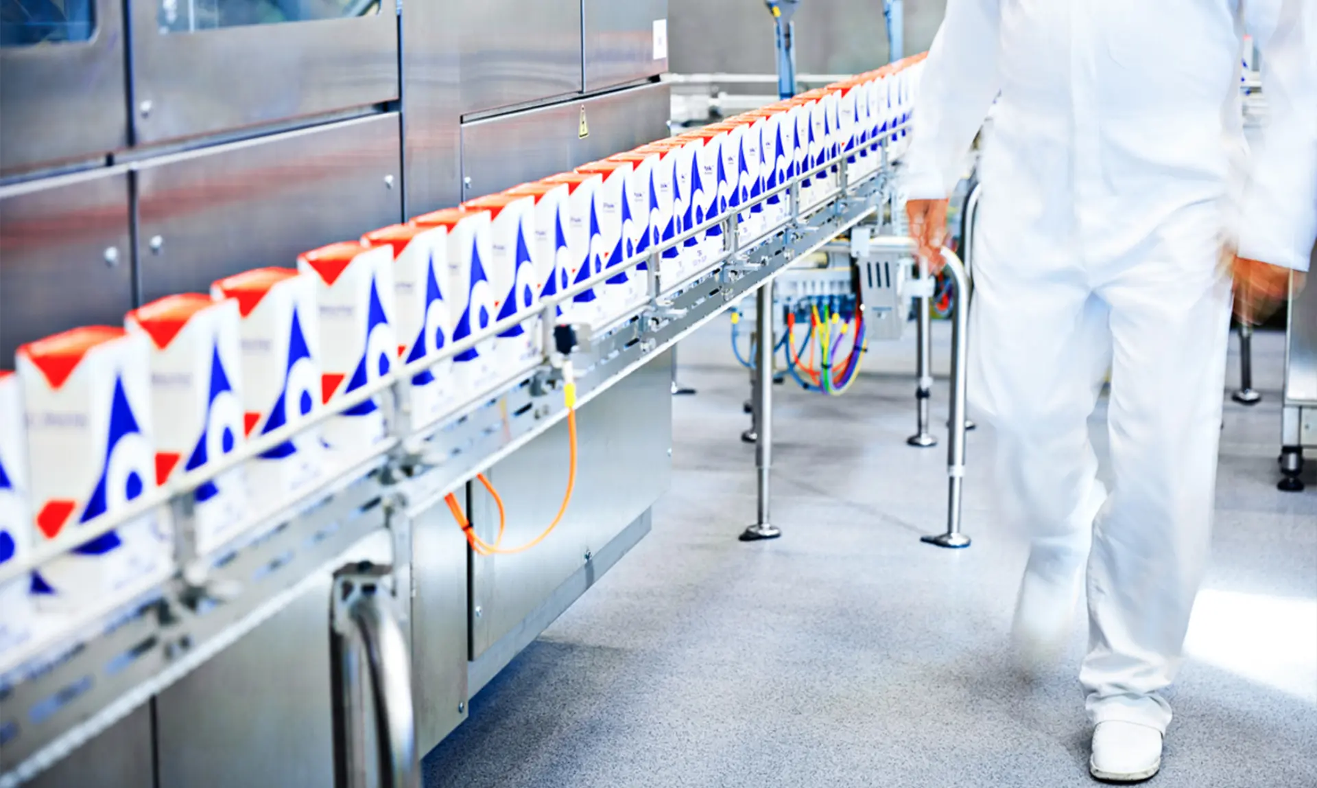 A man in a white uniform walks along a production line, overseeing the manufacturing process.