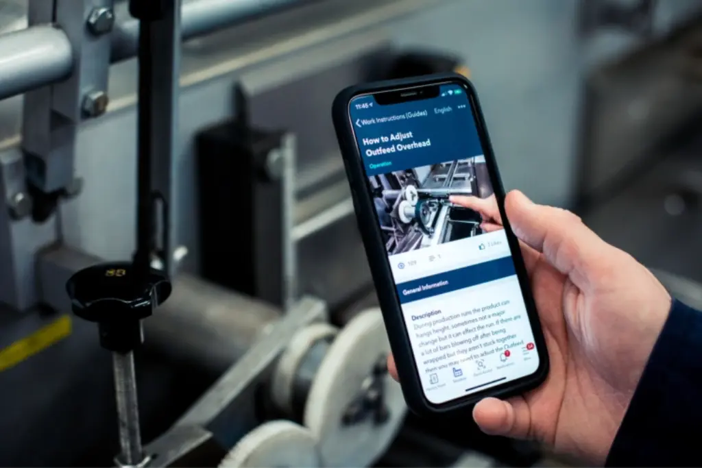 A person holding an iPhone looking at Poka connected worker app.