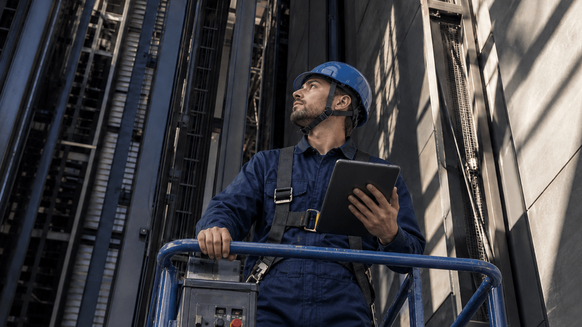 A man wearing a blue hard hat and a safety vest holding a tablet